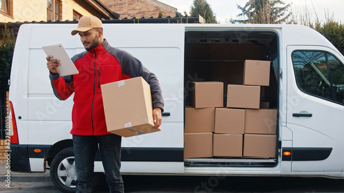 Photos Young man using tablet to view information about the parcel