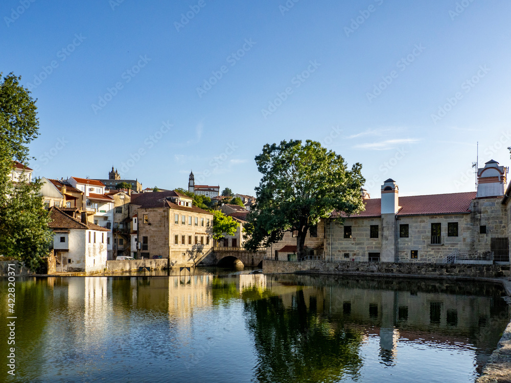 Old buildings in Viseu reflected on a Pavia river, Portugal
