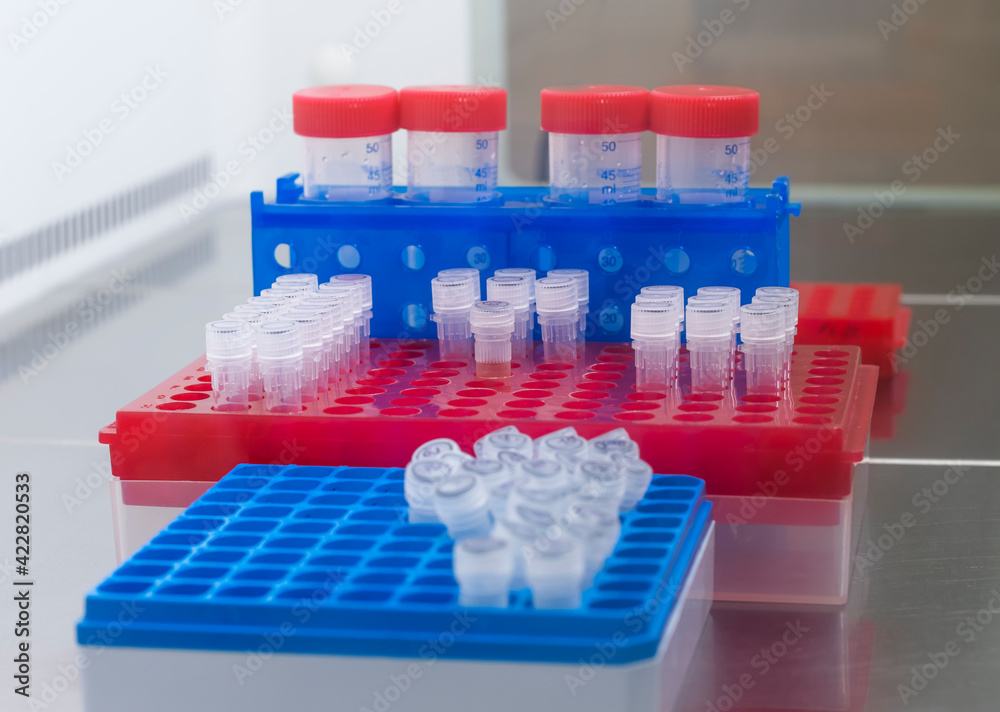 A set of test tubes with reagents, vaccines, antibiotics and bacteria in different laboratory racks in a sterile cabinet. A set of test tubes with reagents, vaccines, antibiotics and bacteria in different laboratory racks in a sterile cabinet.