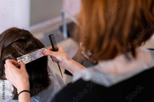 Hairdresser coloring a mature lady's hair in a hairdresser