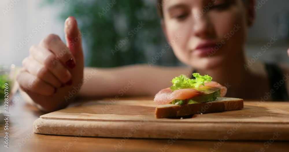 Close up of woman gently placing lettuce leaf onto salmon avocado toast. Healthy eating concept. Close up of woman gently placing lettuce leaf onto salmon avocado toast. Healthy eating concept.