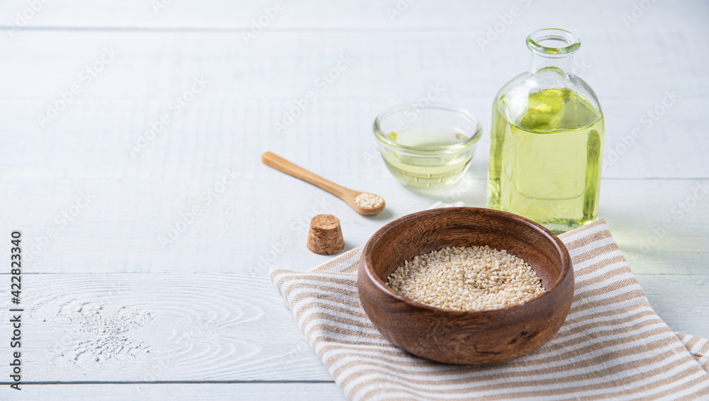Natural vegetable oil from sesame seeds in a clear bottle on the wooden background. Dietary healthy food Natural vegetable oil from sesame seeds in a clear bottle on the wooden background. Dietary healthy food