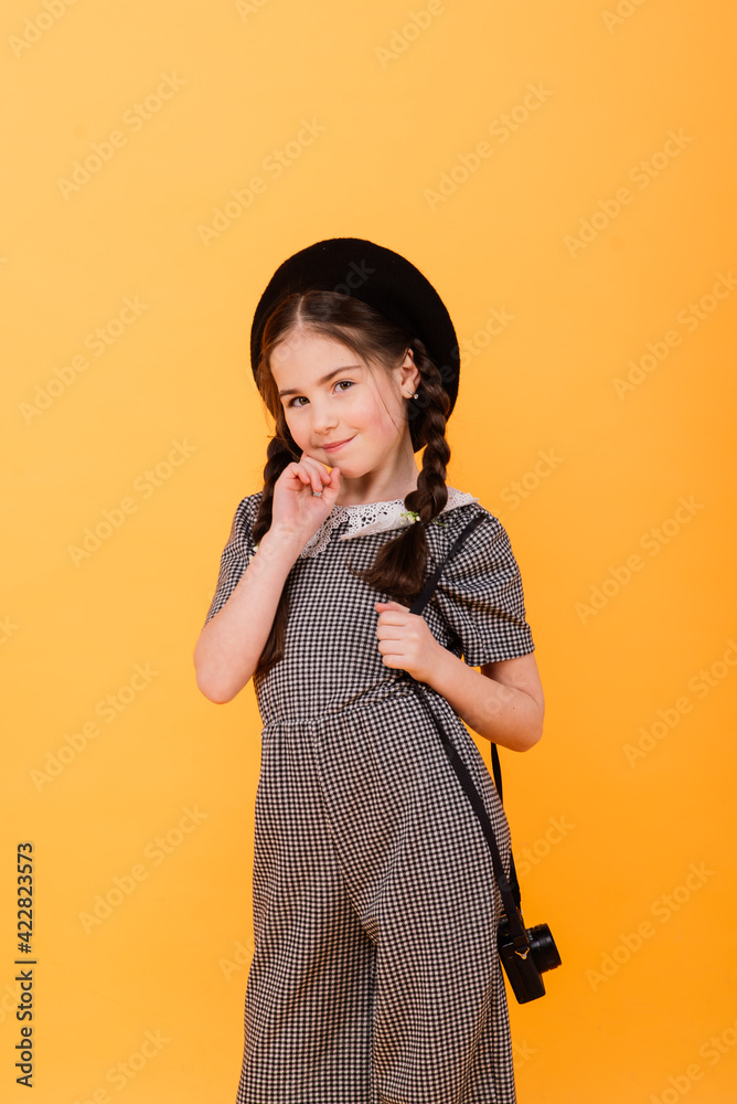 Obraz premium Portrait of baby girl holding photo camera isolated on yellow background