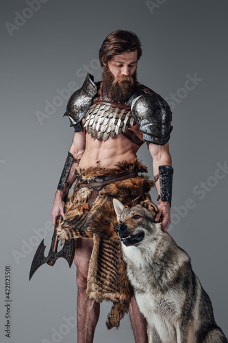 Legendary viking with muscular and naked body posing with his wolf