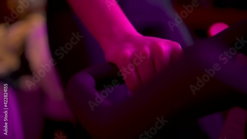 Young girl pedaling on top of the bike during an evening spinning session at home or at the gym. Neon light