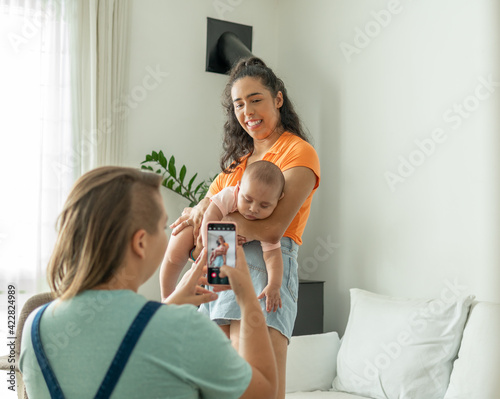 lesbian couple photographing sleepy baby in the living room.