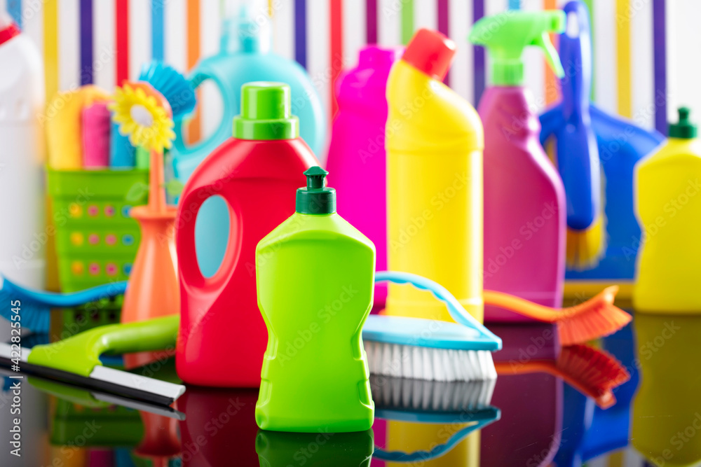 Spring house and office cleaning theme. Colorful set of bottles with clining liquids and colorful cleaning kit on background in the form of colorful stripes. Spring house and office cleaning theme. Colorful set of bottles with clining liquids and colorful cleaning kit on background in the form of colorful stripes.