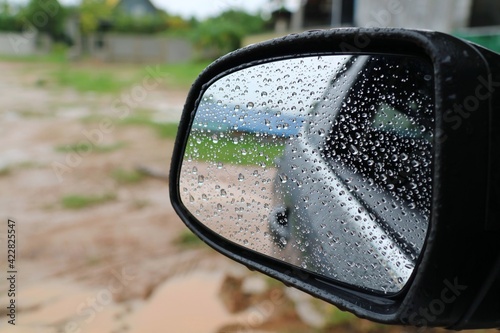 Rain drop on the wing mirror of the car in the raining day. Selective focus. Transportation and nature concept.