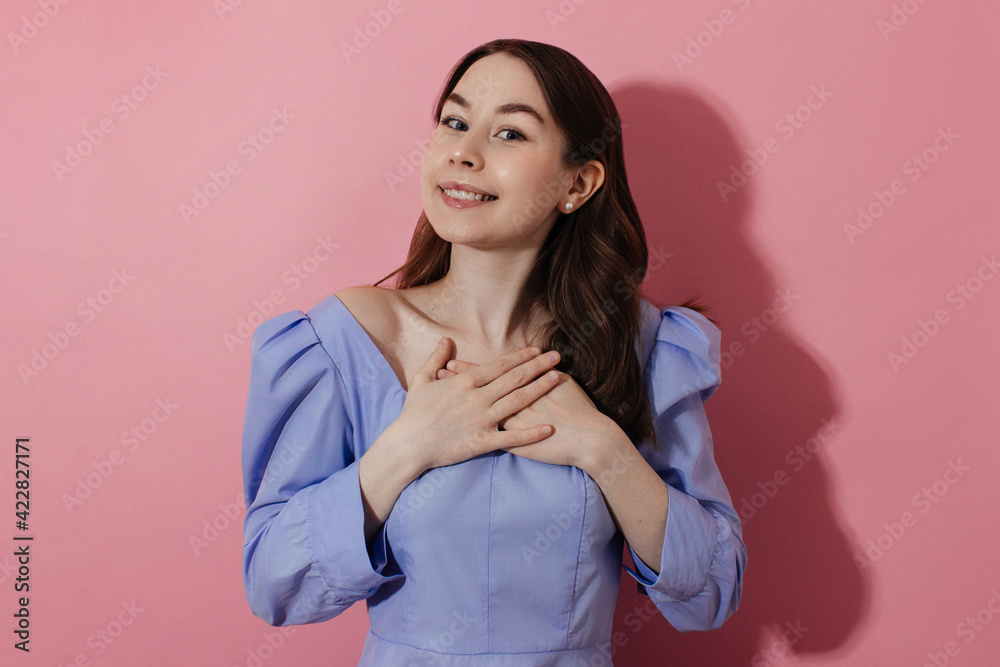 Thankful, grateful young woman keeps hands on cheast, breast looking at ...