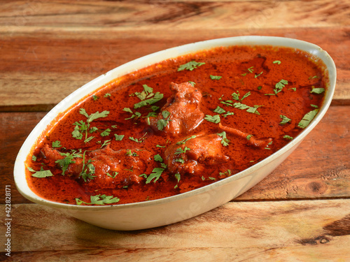 Chicken korma made of indian spices served in a bowl over a wooden rustic background. selective focus