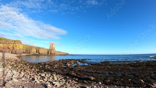 4k real time clip of Old Keiss Castle in Caithness, Scotland, taken from shoreline with rocks, sea and cliffs in foreground. Sunny day with no people. Taken from static position. On North Coast 500. photo