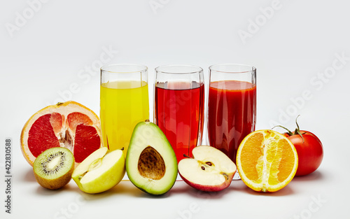transparent glasses with juice and fruits on a light background