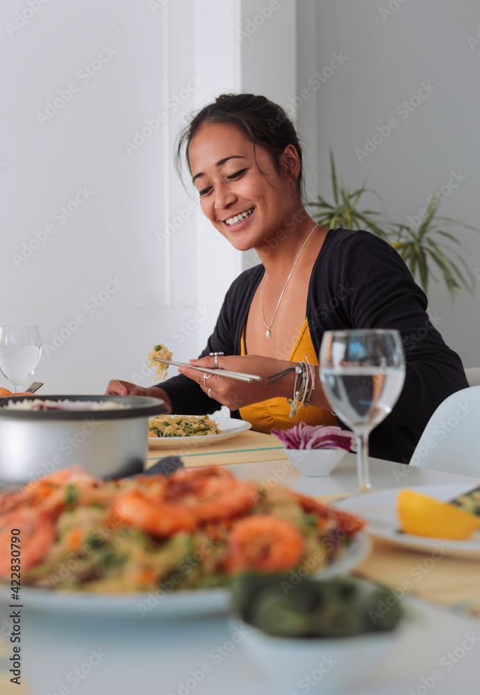 Beautiful young woman eating asian food at home - Woman sharing filipino food with other people