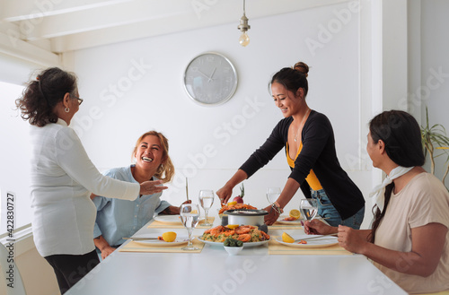 Family of four filipino women sharing lunch together at home - Family spending quality time cooking asian food and eating it together