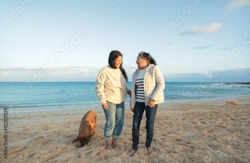 Beautiful senior filipino woman sharing some family time with her daughter - Two women standing in their house garden, surrounded by palm trees - Mother and daughter hugging each other