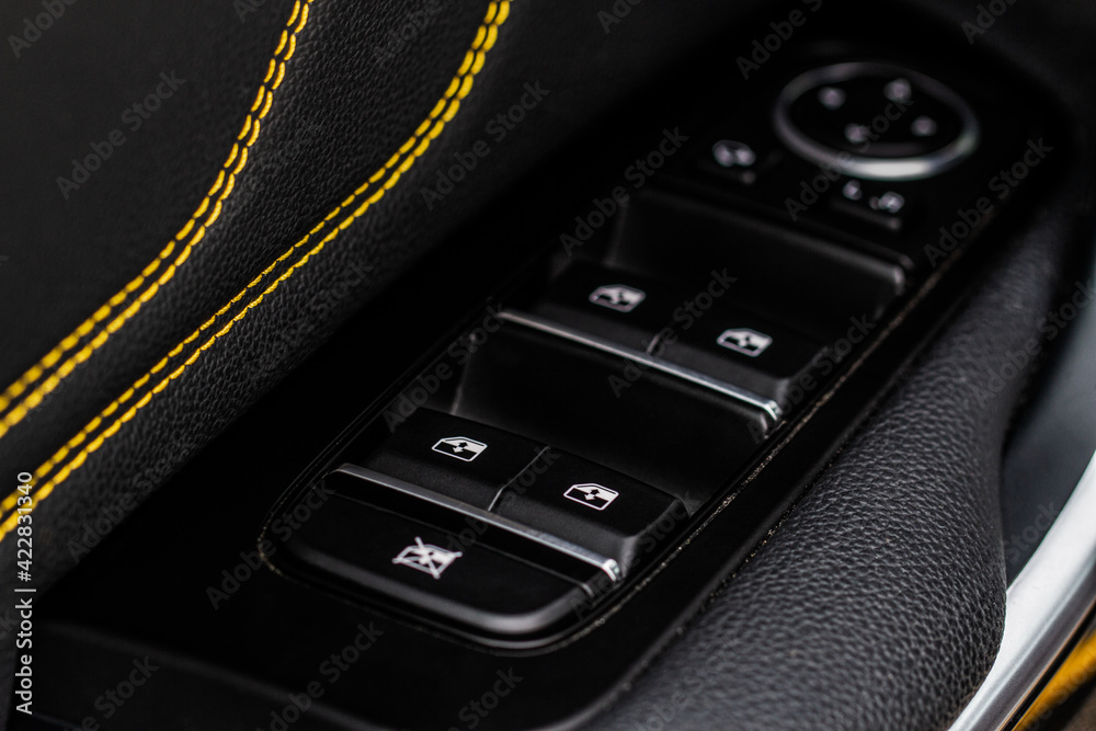 Obraz premium Close up view of button controlling window in modern car interior. Vehicle interior detail. Door handle with windows controls