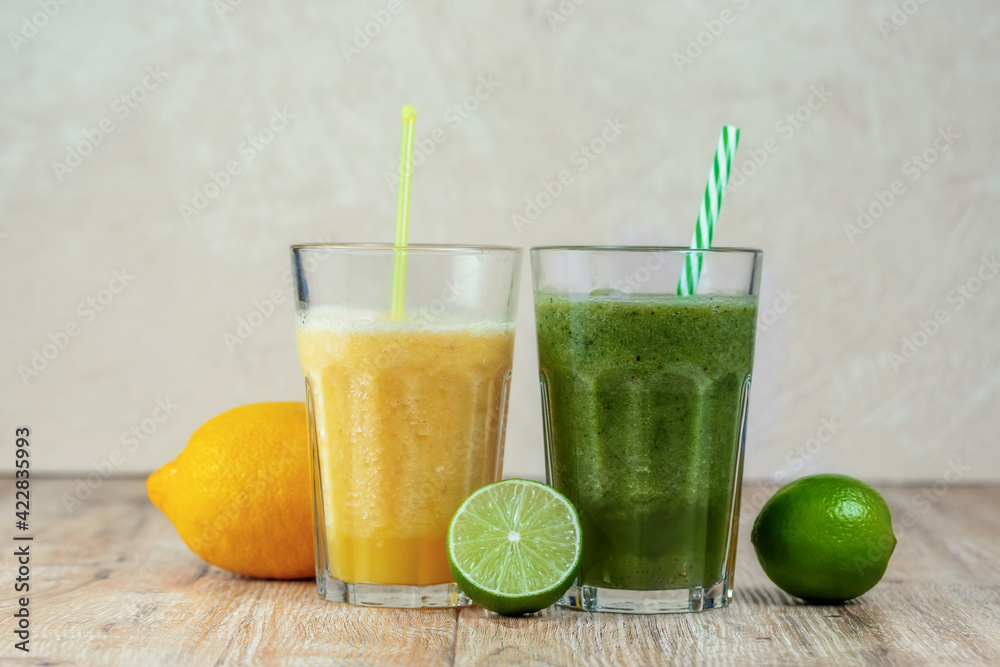 Fototapeta premium Tall glass with kiwi and spinach smoothie surrounded by fruits on a wooden table