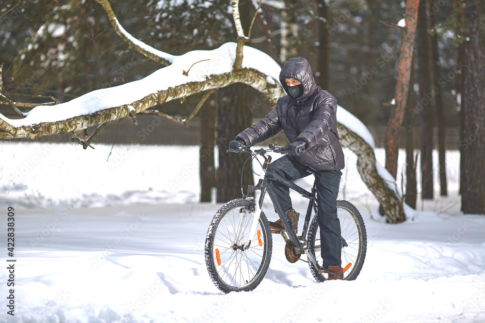 Winter sports. Cycling trips. A young man in black clothes rides a bicycle