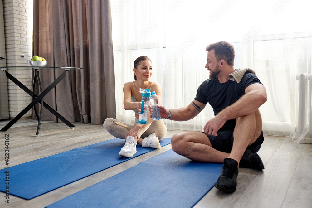 Obraz premium positive couple drink water relaxing after workout training at home