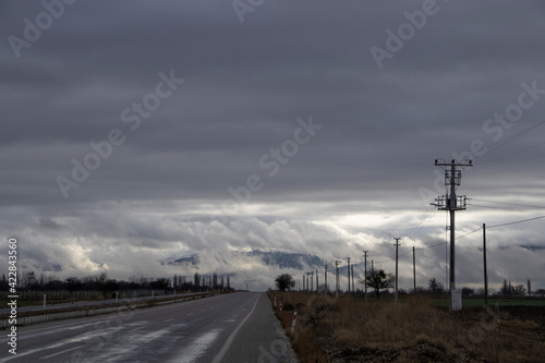 The road to the mountain, snow and heavy fog on the mountain, power poles on the roadside