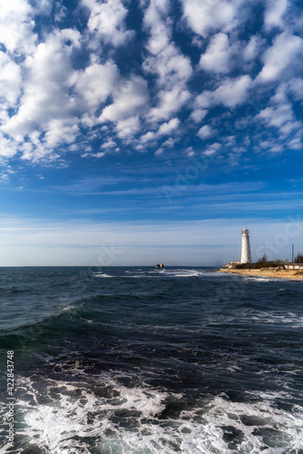 Lone beacon guards the ships. The lighthouse shows the way for boats. Wrecked ship lays nearby