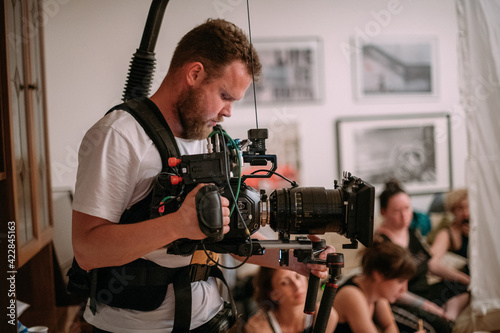 Director of photography with a camera in his hands on the set. Professional videographer at work on filming a movie © Anna