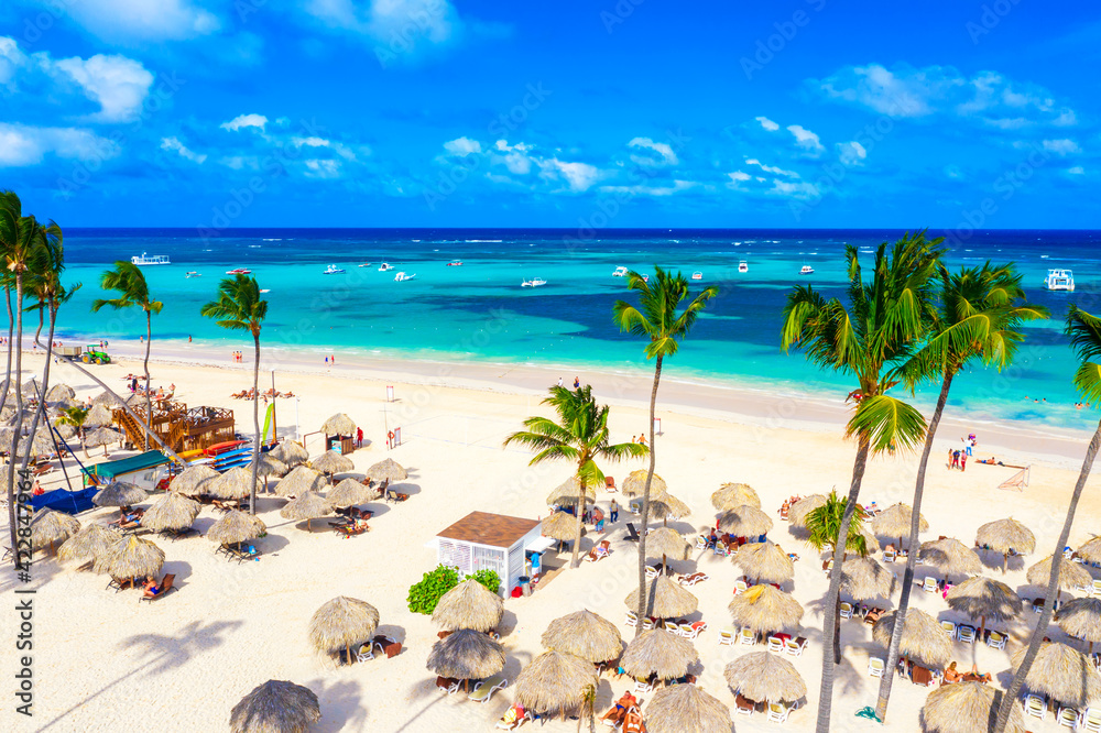 Beach vacation and travel background. Aerial drone view of beautiful atlantic tropical beach with straw umbrellas and palms. Bavaro beach, Punta Cana, Dominican Republic. Beach vacation and travel background. Aerial drone view of beautiful atlantic tropical beach with straw umbrellas and palms. Bavaro beach, Punta Cana, Dominican Republic.