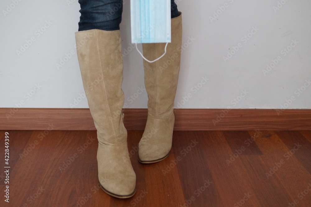 Woman with hight and beige boots and bue mask in times of Covid pandemic Woman with hight and beige boots and bue mask in times of Covid pandemic