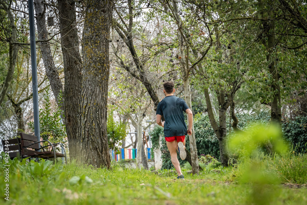 Unrecognized male runner with sportswear working out in the park.