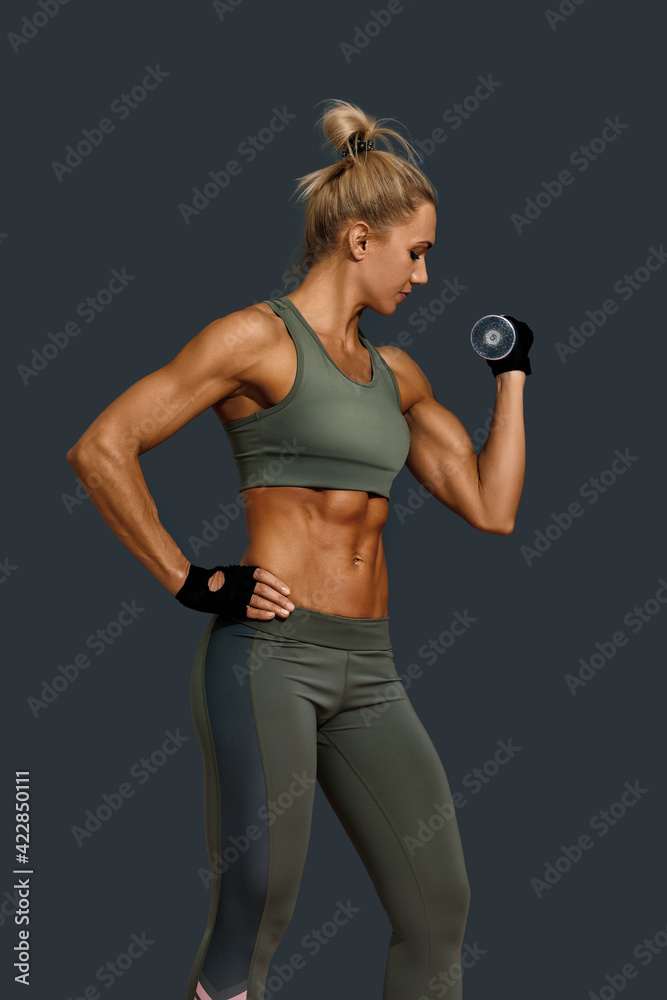 Strong woman in sportswear exercising with dumbbell Strong woman in sportswear exercising with dumbbell