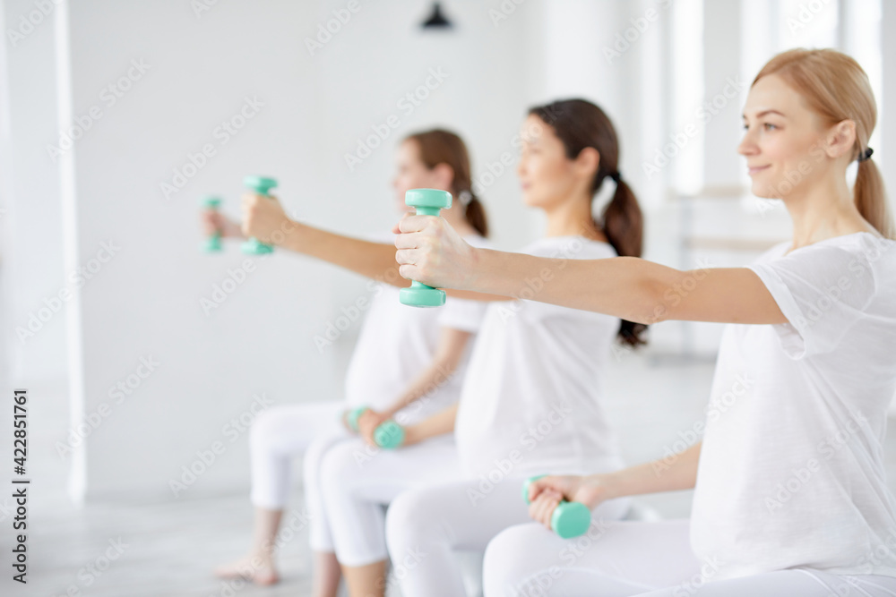close-up photo of pregnant female hands with dumbbells