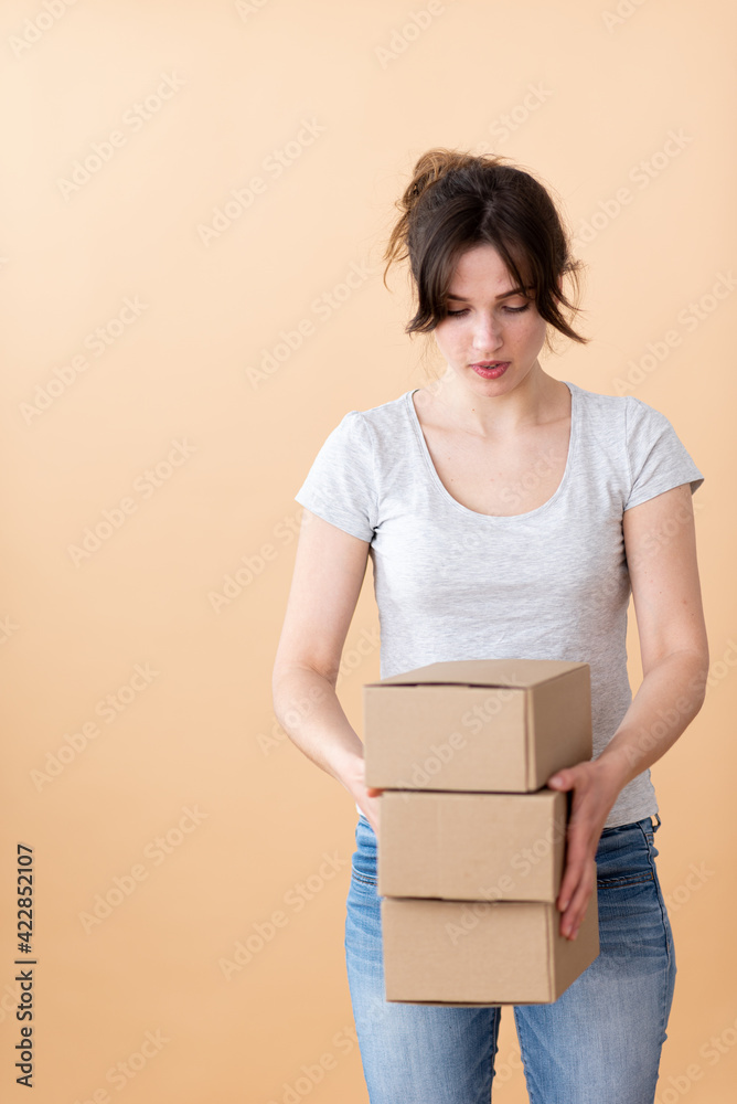 A young postal worker carries three brown cardboard boxes. A young postal worker carries three brown cardboard boxes.