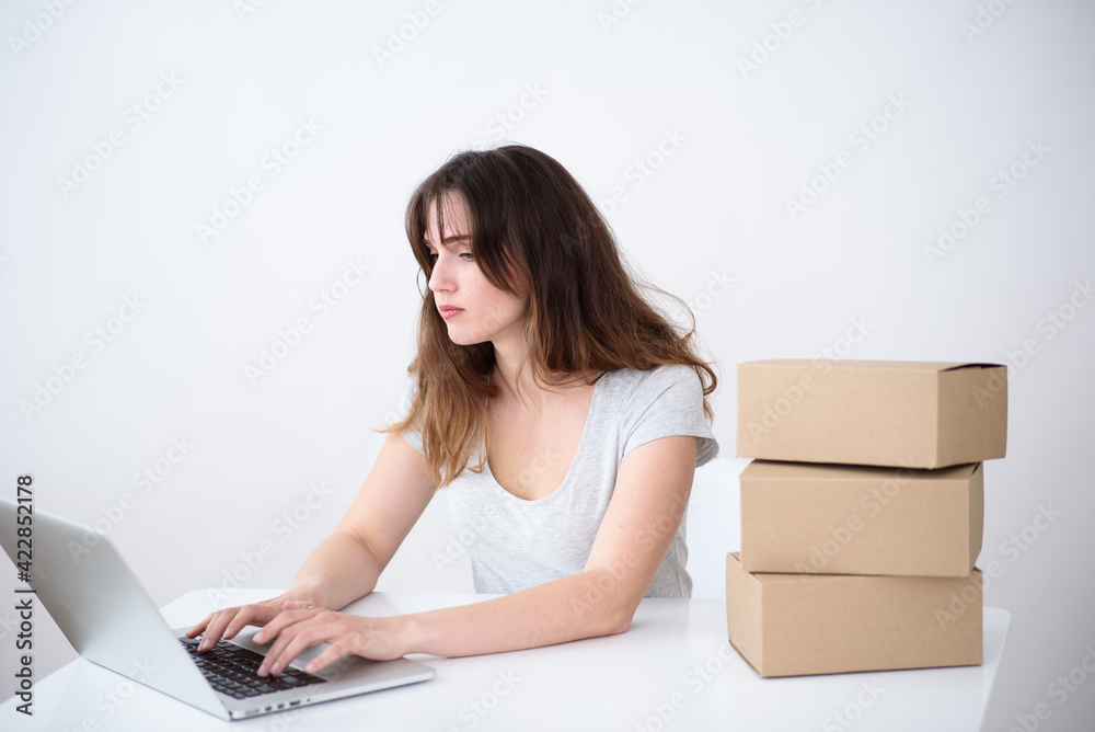 Girl operator typing on a laptop the order for the delivery of three boxes Girl operator typing on a laptop the order for the delivery of three boxes