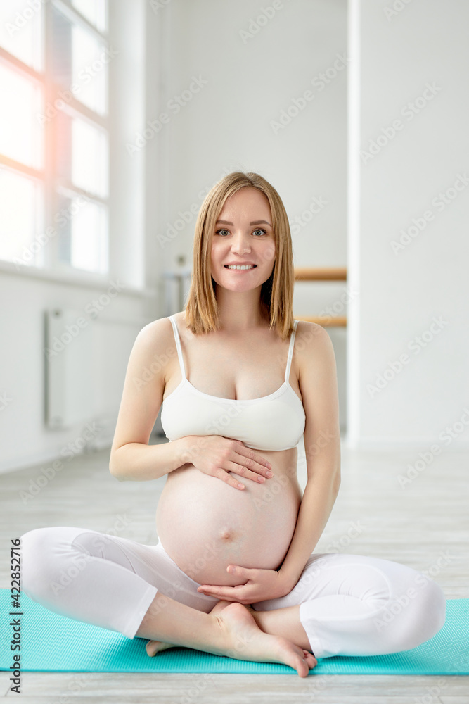 young caucasian female gravid or expectant sit on floor in studio relaxing having rest