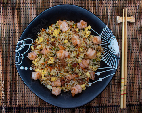 Yakimeshi is rice and eggs, shrimp, vegetables and more in the black plate. Asian food.