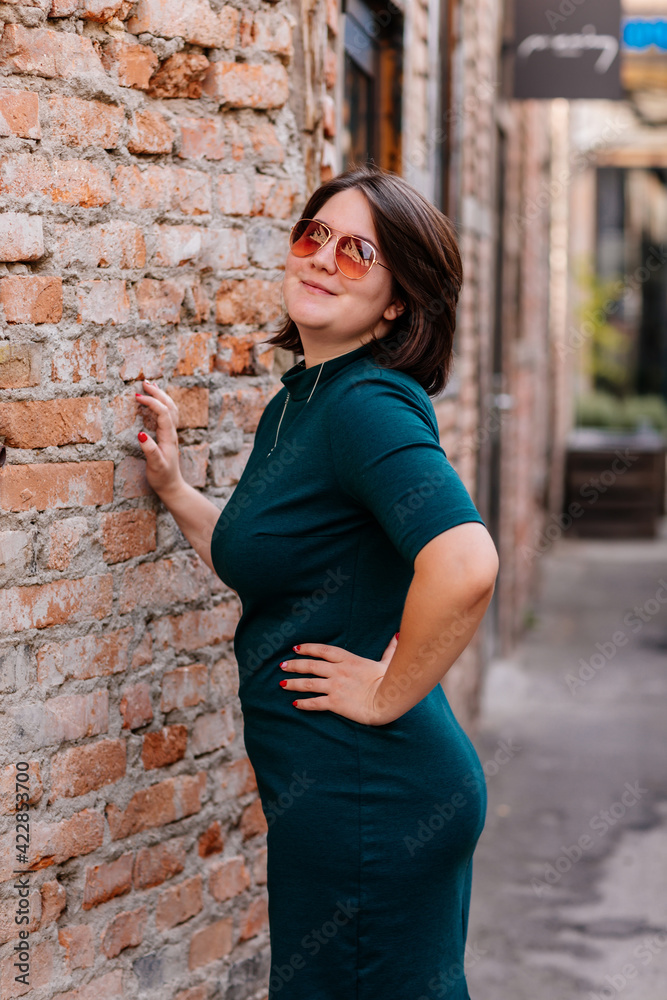 Portrait of stylish young pretty hipster woman in sunglasses and green dress, vintage urban background, street photo, brick wall, looking away, Happy beautiful girl, body positivity casual clothes Portrait of stylish young pretty hipster woman in sunglasses and green dress, vintage urban background, street photo, brick wall, looking away, Happy beautiful girl, body positivity casual clothes