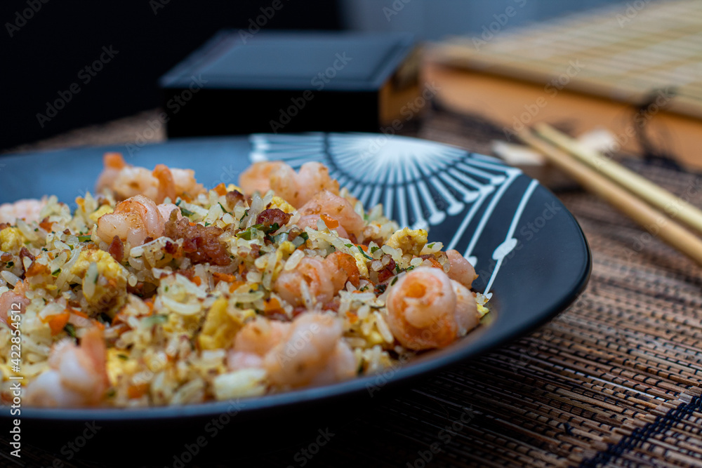 Yakimeshi is rice and eggs, shrimp, vegetables and more in the black plate. Asian food.