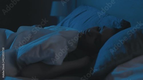 Sleep disorder. Night insomnia. Nightmare stress. Disturbed anxious woman cant rest tossing turning asleep with closed eyes in bed late in dark home bedroom with blue moonlight.
