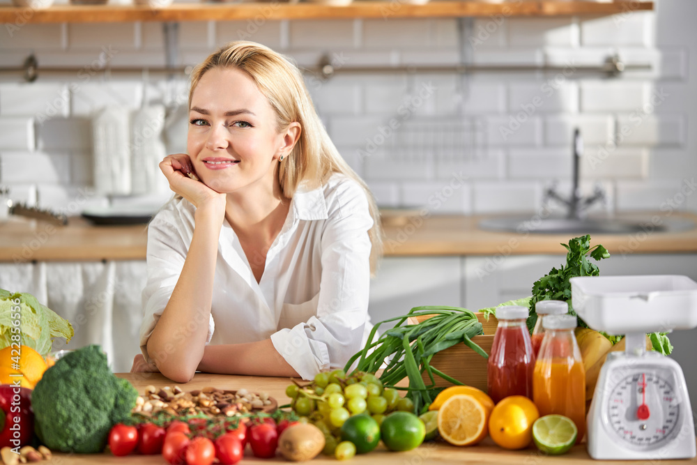 beautiful woman of european appearance like healthy eating, stand by table with fresh food
