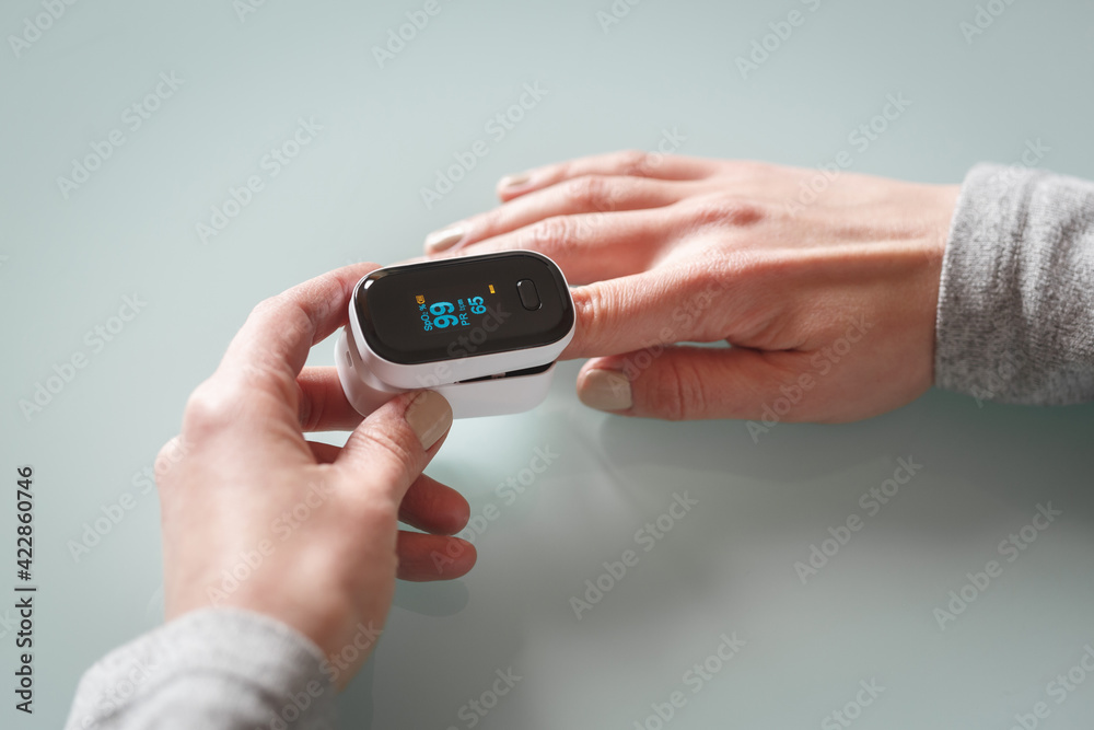 Female patient hand measuring oxygen saturation and pulse using portable oximeter.
