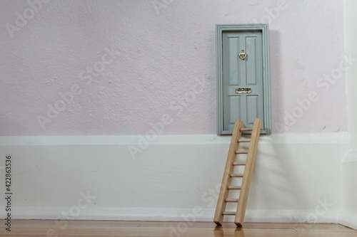 A small tooth fairy door with a ladder in a child's room for pretend play. 