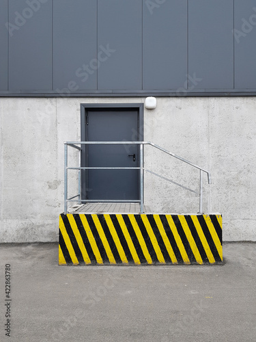 door on the facade, concrete wall of the building, technical or fire exit, loading area