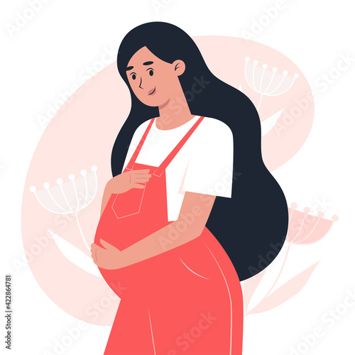 Young pregnant woman in overalls hugging belly with hands, pregnancy and motherhood