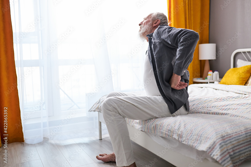 people, healthcare and problem concept - sad senior man suffering from pain in back or reins at home people, healthcare and problem concept - sad senior man suffering from pain in back or reins at home