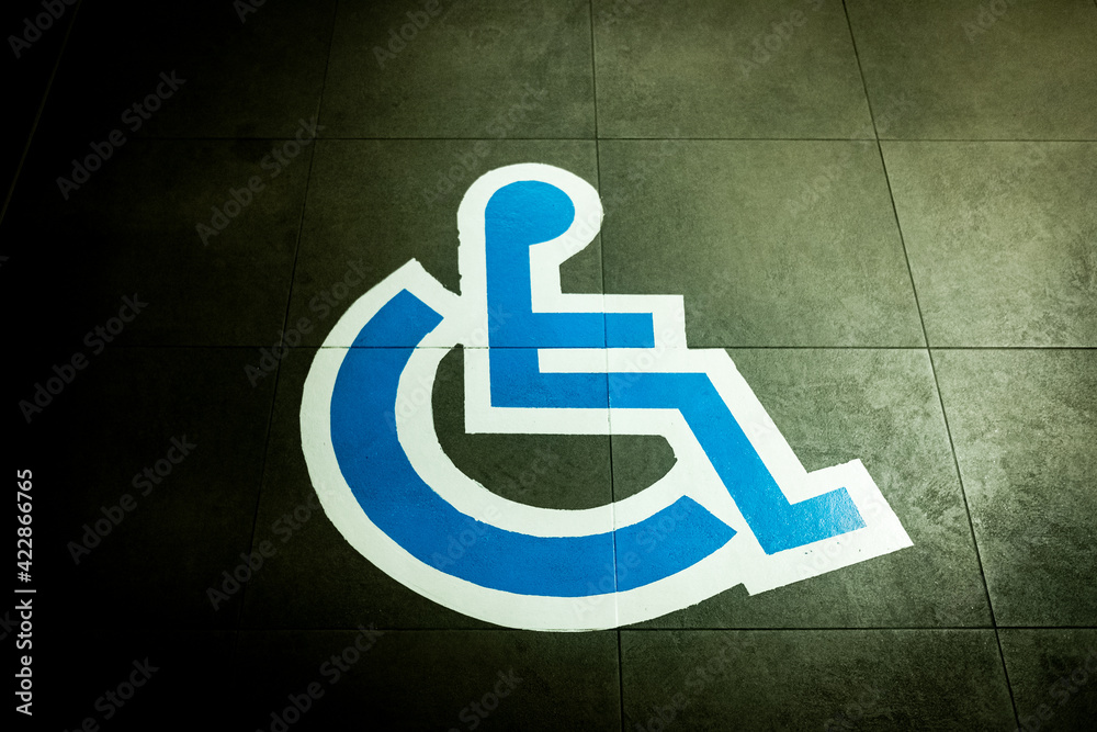 Sign painted on the ground in a large car park reserved for people with disabilities