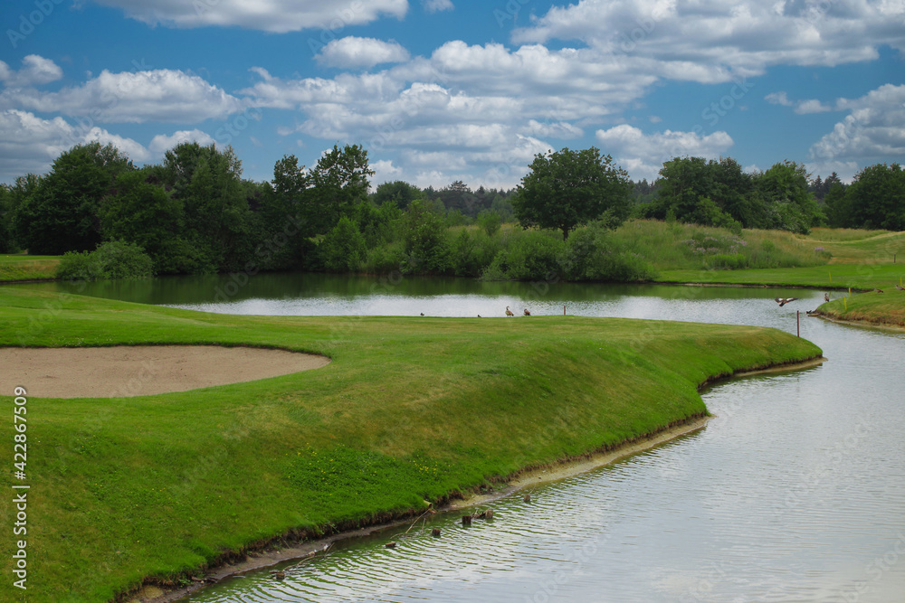 Beautiful golf course landscape with sand trap, water hazard and dense vegetation Beautiful golf course landscape with sand trap, water hazard and dense vegetation