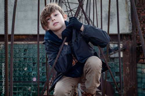 Fashionable boy ruffer climbs metal structures at heights in an abandoned factory. Dangerous entertainment for children. Parkour. Extreme sports. Danger of walking. Suicide. Troubled teenager. Tomboy