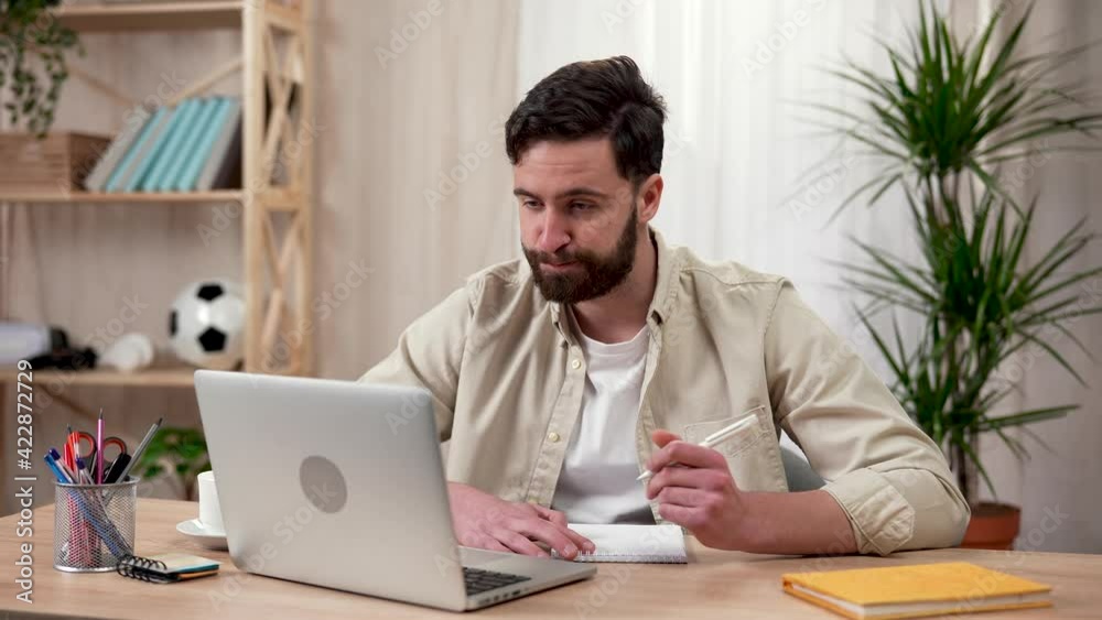 Caucasian man sitting at a desk in his home office, participating in a video conference, talking, taking notes, showing a thumb up gesture and clapping his hands. Close up. Slow motion ready 59.97fps. Caucasian man sitting at a desk in his home office, participating in a video conference, talking, taking notes, showing a thumb up gesture and clapping his hands. Close up. Slow motion ready 59.97fps.