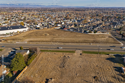 Fotografie Aerial view of empty lots with a residential neighborhood and Boise, Idaho in the background