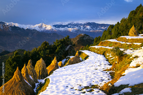 Landscape with snow and mountains. Sunset view of a scenic village during winter in the backdrop of the Himalayan mountains. Himachal Pradesh, India.